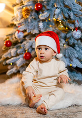 Adorable little baby boy in a christmas outfit sitting on a soft fake fur in front of a christmas tree.  Merry Christmas and Happy Holidays!