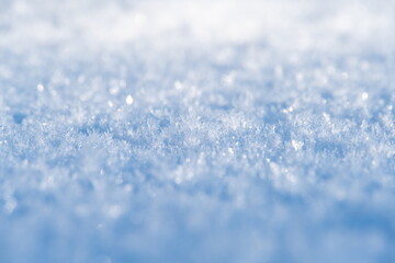 White ice crystals in bright sunlight. Macro photography of ice crystal texture. Snow crystals close-up on a bright frosty winter day. White sparkling snow surface close up.