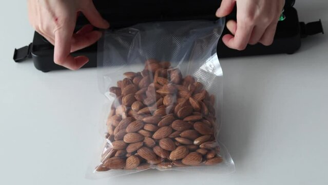 Vacuum packing almond nuts for long term storage. It uses a vacuum packer for long term storage of products. Vacuum packaging machine in the home kitchen.