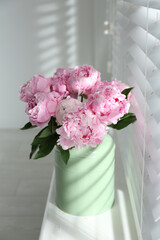 Bouquet of beautiful peonies on window sill