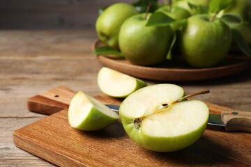 Cut fresh green apple on wooden table, closeup