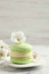 Obraz na płótnie Canvas Green macaron and flowers on white marble table