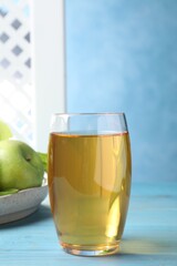 Glass of fresh apple juice on light blue wooden table
