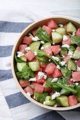 Delicious salad with watermelon, cucumber, arugula and feta cheese on white wooden table, flat lay