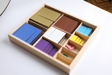 Set of wooden geometrical figures in box isolated on white. Montessori toy
