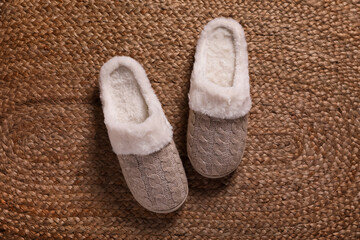 Fototapeta na wymiar Pair of warm stylish slippers on wicker carpet, top view