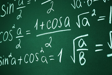 Many different math formulas written on chalkboard, closeup