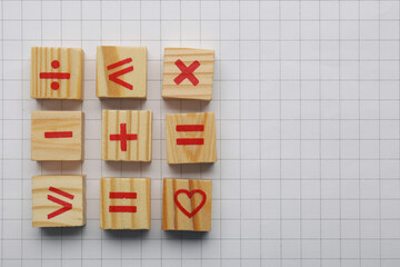 Wooden cubes with mathematical symbols and heart on sheet of grid paper, flat lay. Space for text