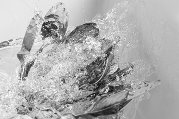 Washing silver spoons, forks and knives under stream of water in kitchen sink, above view