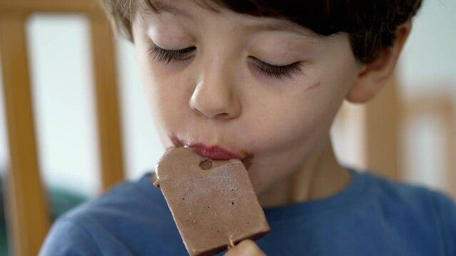 Child mouth covered with chocolate icecream. Little boy taking a bite of ice cream sweet dessert