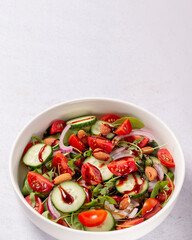 Healthy salad with spelt, oranges, pomegranate seeds. greens and nuts on light background, minimal style