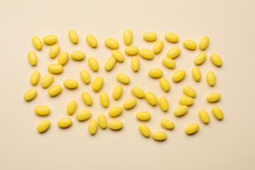 Many tasty dragee candies on yellow background, flat lay