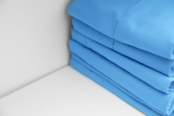 Light blue medical uniforms on white rack, closeup. Space for text