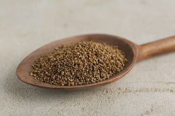 Spoon of celery seeds on light grey table, closeup