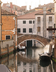 Fototapeta na wymiar Architectural detail of buildings and brick bridge in Venice, Italy during a morning with mist