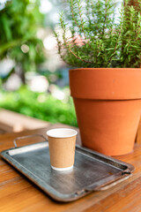 Closeup of blank craft paper coffee cup on the wood table. Space for you advertising. Horizontal mockup, blurred background