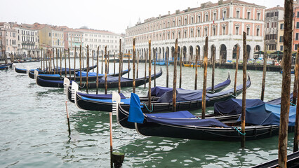 Fototapeta na wymiar Foggy Venice in Winter, empty gondolas stopped at the city center dock 