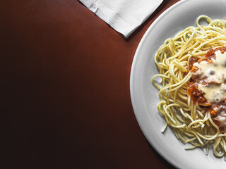 Unstirred spaghetti on a plate, accompanied by a tissue on a wooden table.