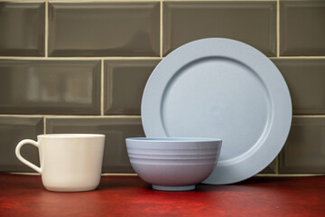 blue   dinner plate bowl with white china cup stacked in the kitchen on a red linoleum work top