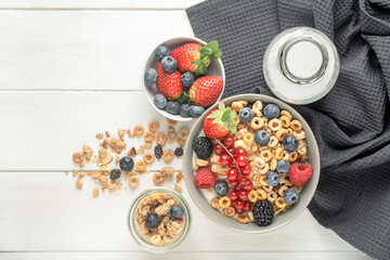 Cereal bowls with fruit and a bottle of milk on a gray napkin on a white table. Healthy eating concept. Front view