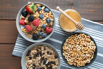 Cereal bowls with berries and honey on a gray striped napkin on a white table. Healthy eating concept. Front view.