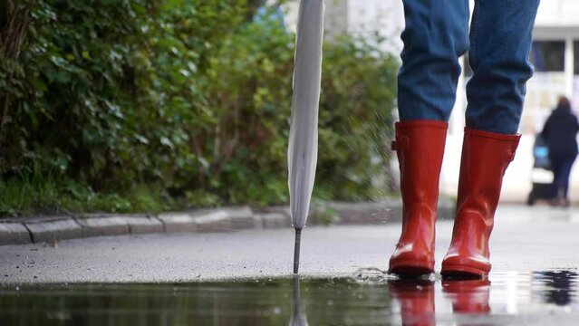 Woman in bright orange rain boots having fun in city, closeup
