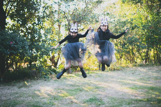 girls with rabbit masks jumping in the garden