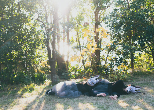 girls with rabbit masks laying down on the grass