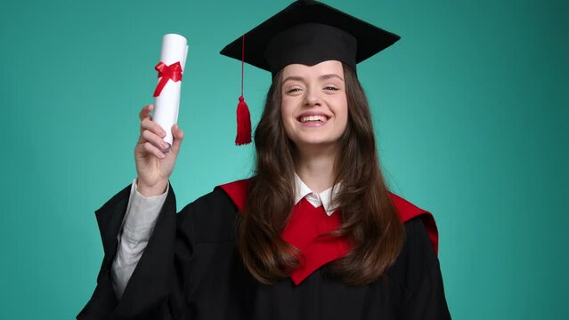 Portrait of caucasian, brunette-haired girl enjoying graduation ceremony. Close-up shot of a beautiful woman in black hat and gown holding her diploma. High quality 4k footage