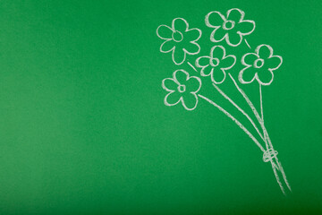 A bouquet of flowers drawn in chalk on a green blackboard. Concept Teacher's Day.