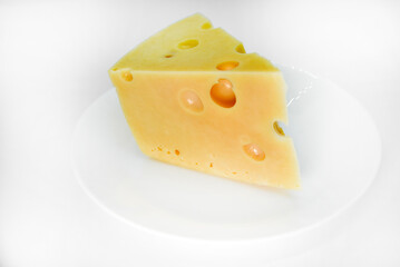 A large piece of cheese on a white background. A triangular piece of cheese with holes.