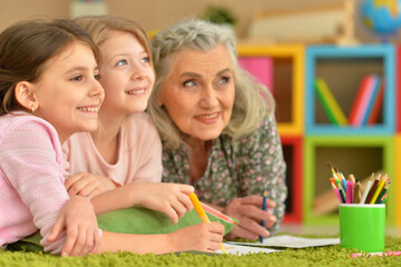 grandmother and granddaughters doing homework together at home