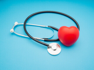 Top view of a stethoscope and a red heart shape on a blue background