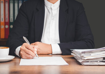 Businessman in a suit signing a lease contract or agreement while sitting at the table