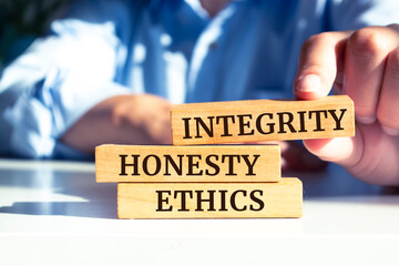Closeup on businessman holding a wooden blocks with text 'integrity, HONESTY, ETHICS', business concept