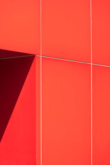Sunlight and shadow on surface of door frame on red aluminum composite tile wall of modern office building in minimal style and vertical frame