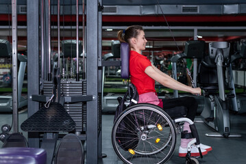 Obraz na płótnie Canvas Woman in a wheelchair lifting weight in gym