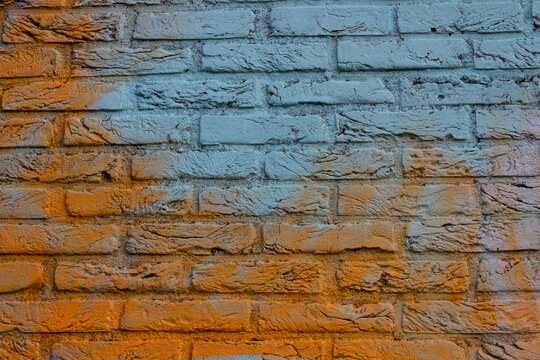 Close-up of light blue and orange graffiti on brick wall