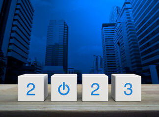 2023 start up business icon on white block cubes on wooden table over modern office city tower and...