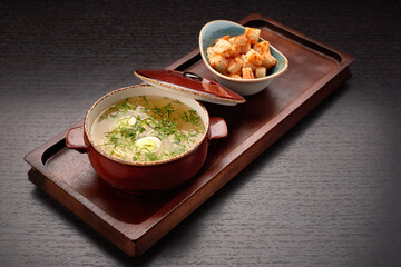 Chicken broth with quail eggs, on a wooden board
