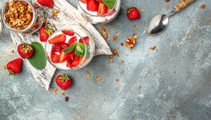 Fototapeta na wymiar strawberry parfaits with fresh fruit, yogurt and granola on white table, glass jar. Healthy breakfast. Long banner format. top view