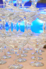 empty champagne glasses in pyramid or tower on table at wedding reception, alcohol bar, catering in restaurant