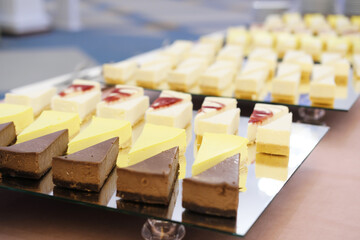 Chocolate, lemon, vanilla and strawberry cheesecakes stand in a row on mirrored trays