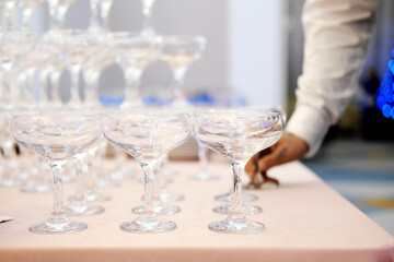 Empty wine or champagne glasses on table are in pyramid. The waiter arranges glasses in a pyramid