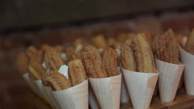 Fried sugar coated churros for sale in white paper cones.