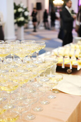 A pyramid of champagne glasses at a party against the backdrop of a hall with guests. champagne pyramid