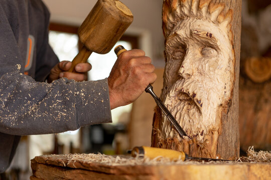 close up of hand carving wood spirit sculpture by skillful artisan wood worker 