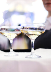The waiter is holding a tray with two glasses of champagne. Catering for the event