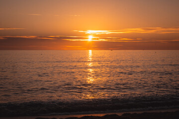 Obraz premium Sunset sun over horizon at sea in out of focus