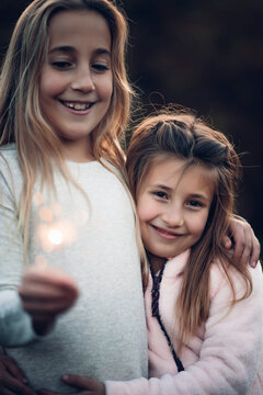 Two beautiful girls have fun with the sparks of a flare.